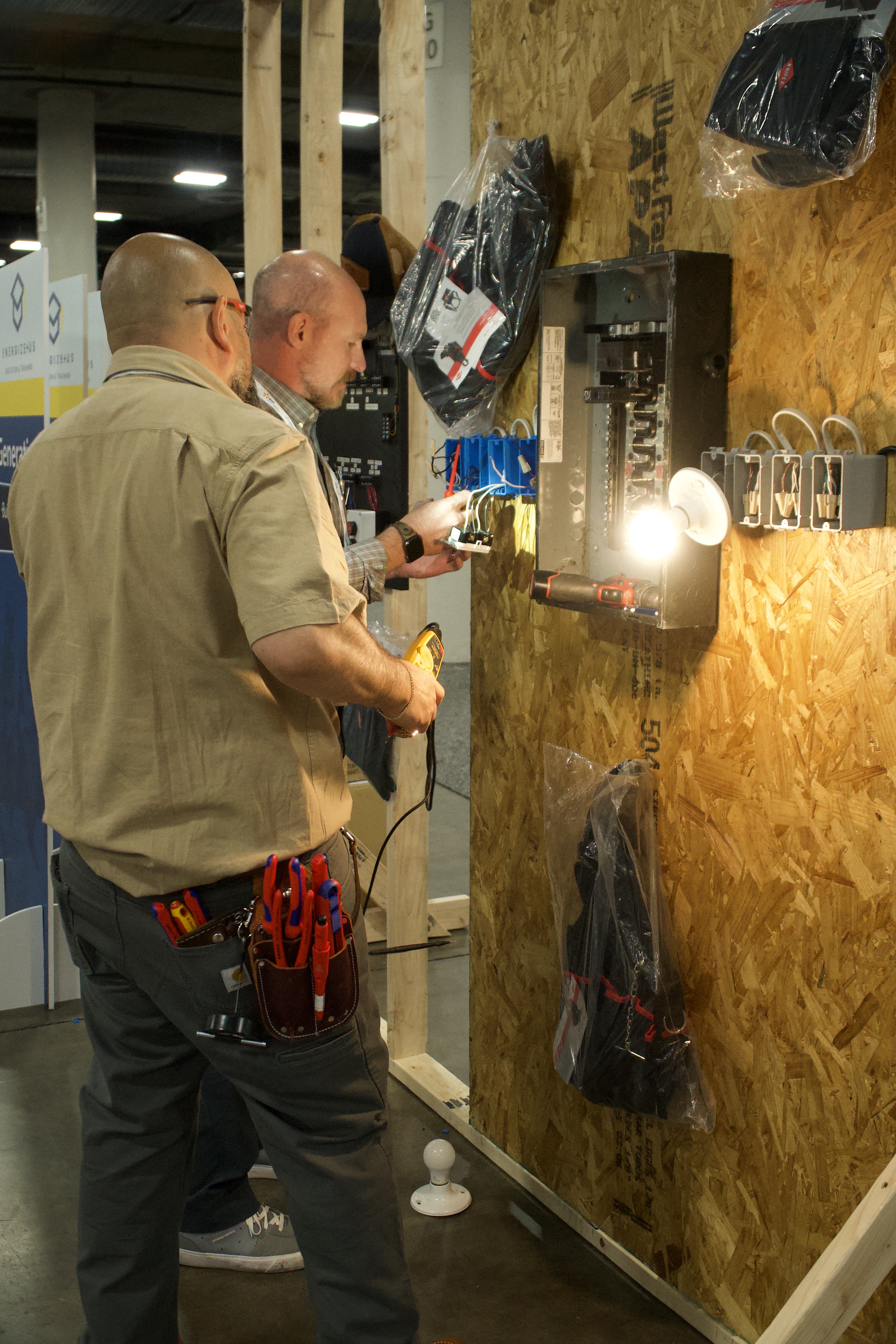 Two participants examining equipment at an electrical training display