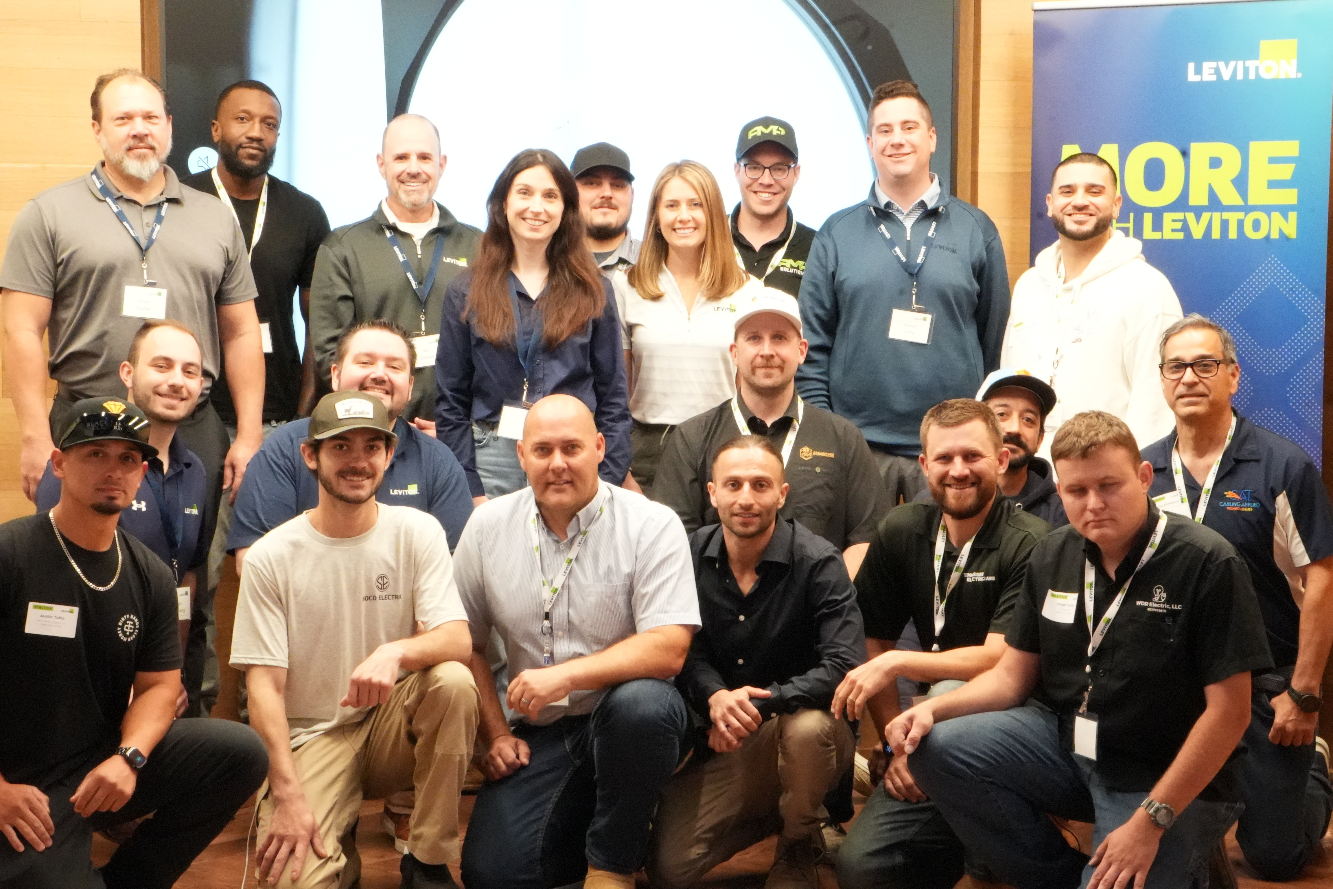 Contractors and event participants gathered beside Leviton signage