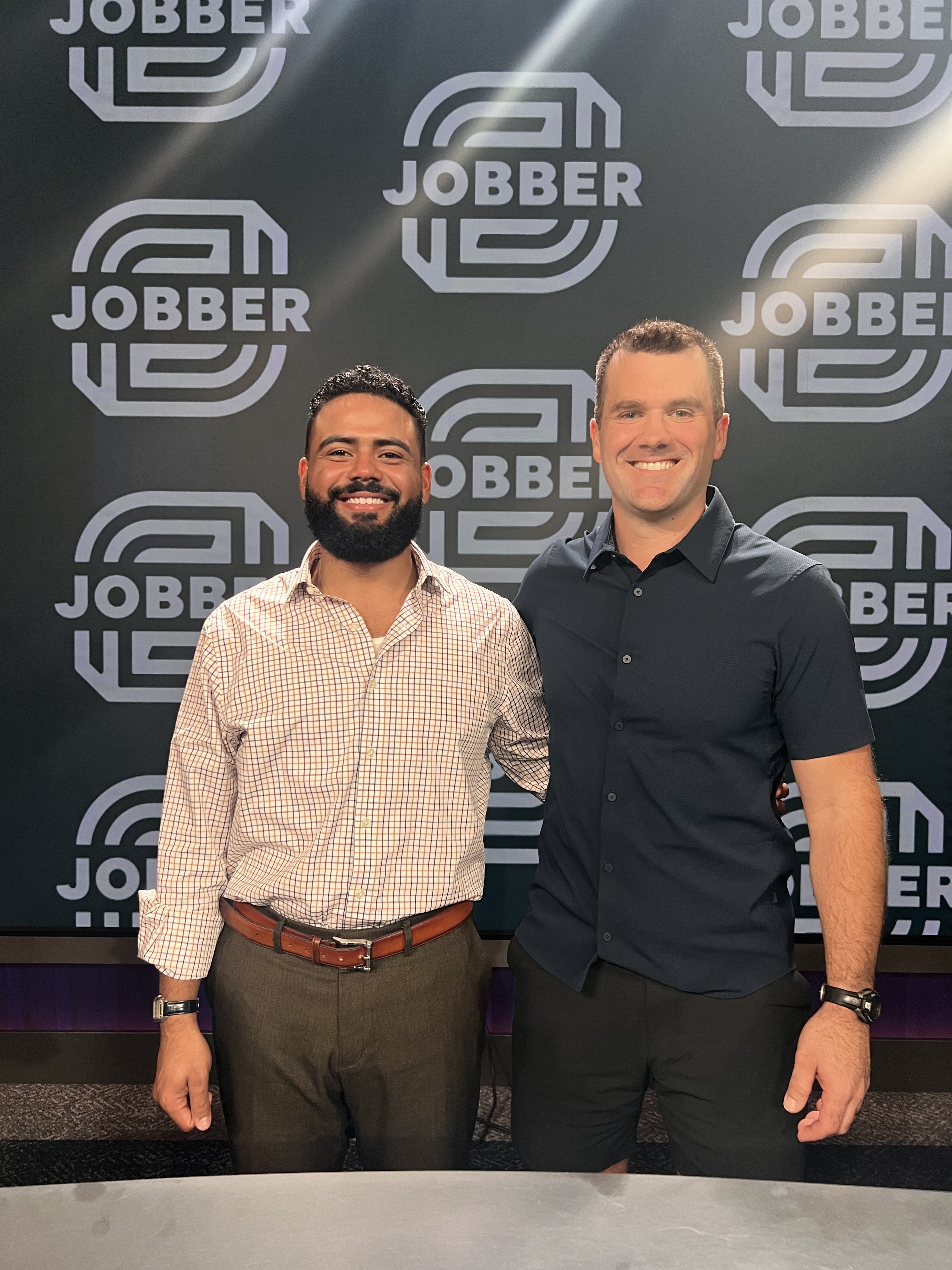 Two attendees standing before a Jobber backdrop during the Las Vegas visit
