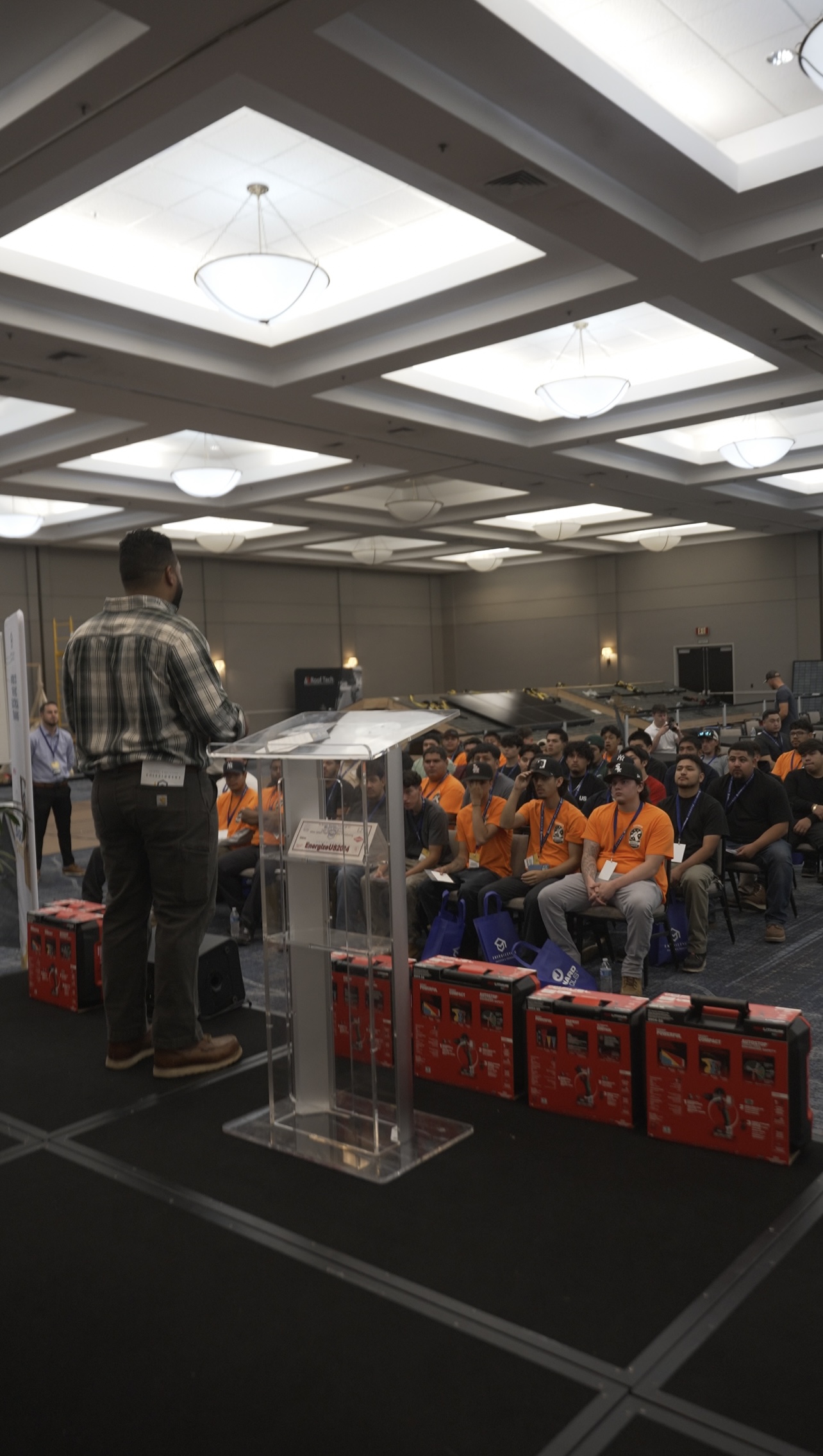 Presentador frente a un atril de Energize Us EDU hablando a asistentes sentados